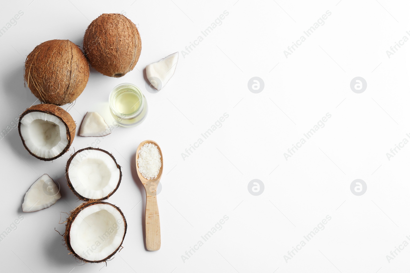 Photo of Jar of natural organic oil and coconuts on white background, top view