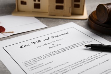 Photo of Last will and testament near house model, gavel on light grey table, closeup