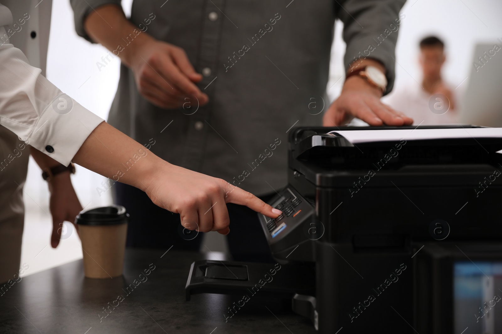 Photo of Employees using modern printer in office, closeup