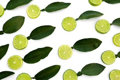 Photo of Fresh lime slices and green leaves on white background, flat lay