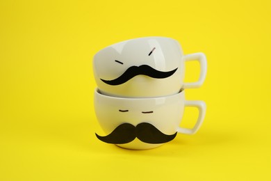 Photo of Men's faces made of cups, fake mustaches on yellow background
