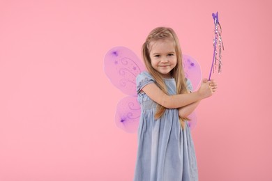 Photo of Cute little girl in fairy costume with violet wings and magic wand on pink background, space for text