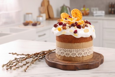 Delicious Easter cake with dried fruits and willow branches on white marble table in kitchen. Space for text