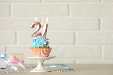 Photo of 21th birthday, coming of age party. Delicious cupcake with number shaped candles on table, space for text