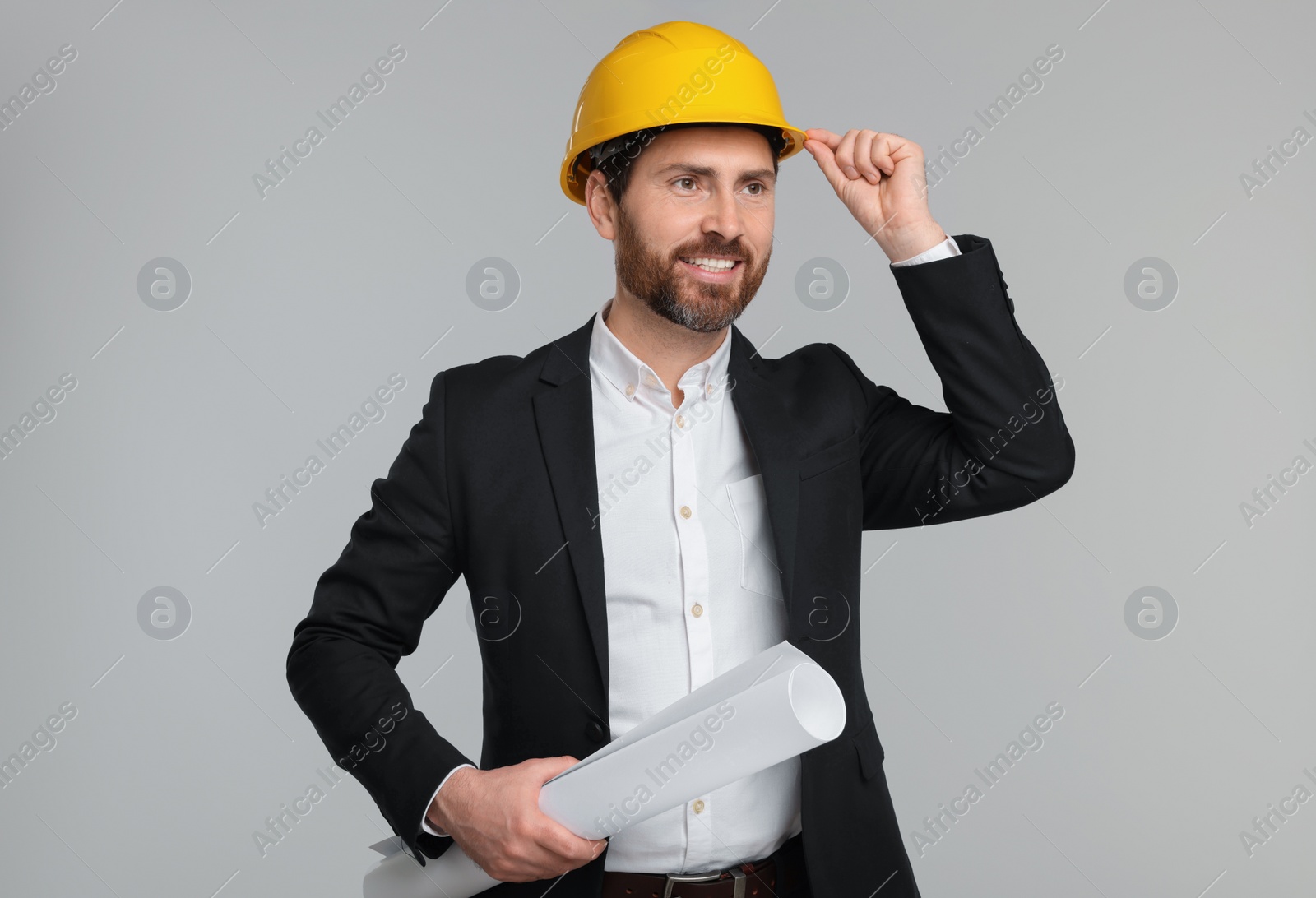 Photo of Architect in hard hat with draft on gray background