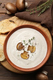 Photo of Fresh homemade mushroom soup in ceramic bowl on wooden table, flat lay