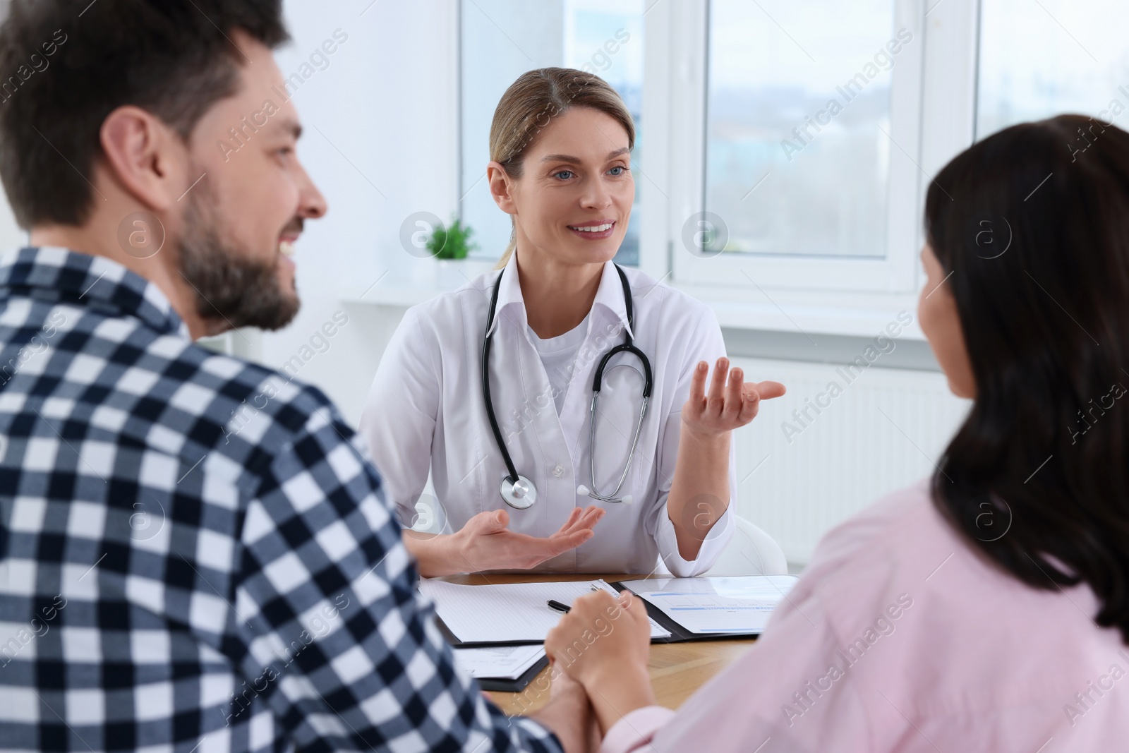 Photo of Couple having appointment with fertility doctor in clinic. Patient consultation