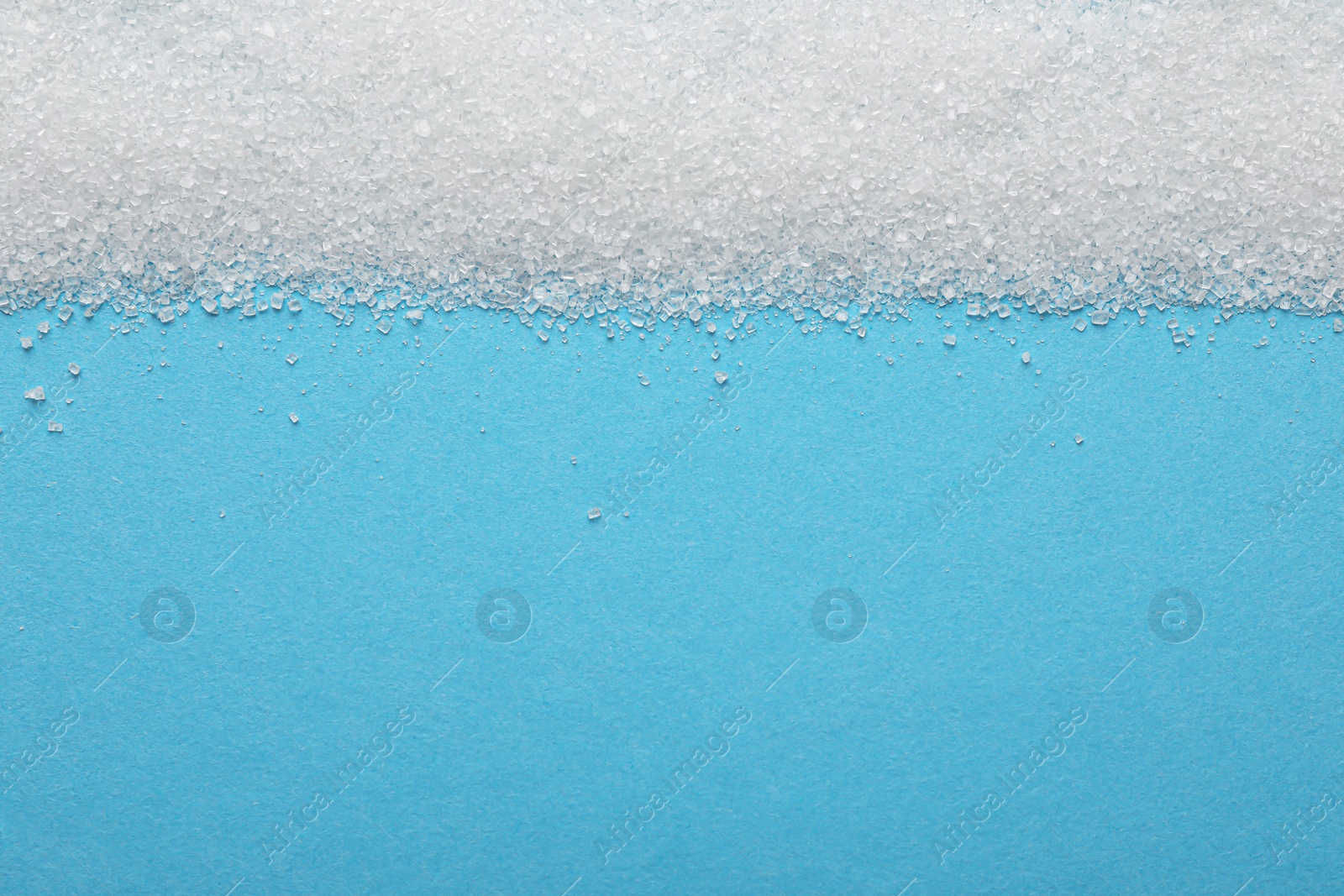 Photo of Granulated sugar on light blue background, top view. Space for text