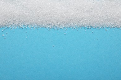 Photo of Granulated sugar on light blue background, top view. Space for text