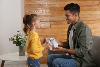 Photo of Man receiving gift for Father's Day from his daughter at home