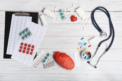 Flat lay composition with stethoscope and pills on wooden background. Cardiology service