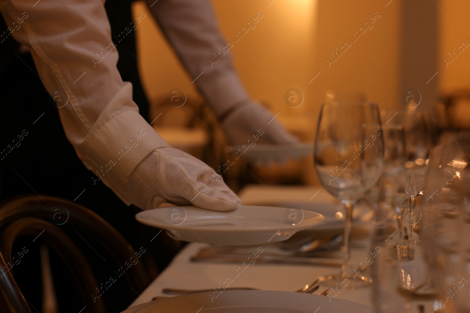 Photo of Woman setting table in restaurant, closeup. Professional butler courses