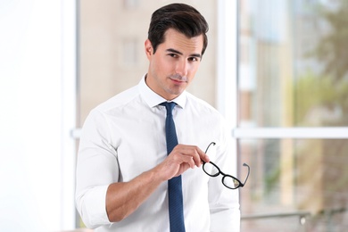 Handsome young man in stylish clothes with glasses indoors