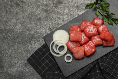 Photo of Cooking delicious goulash. Raw beef meat, onion and parsley on grey table, flat lay. Space for text