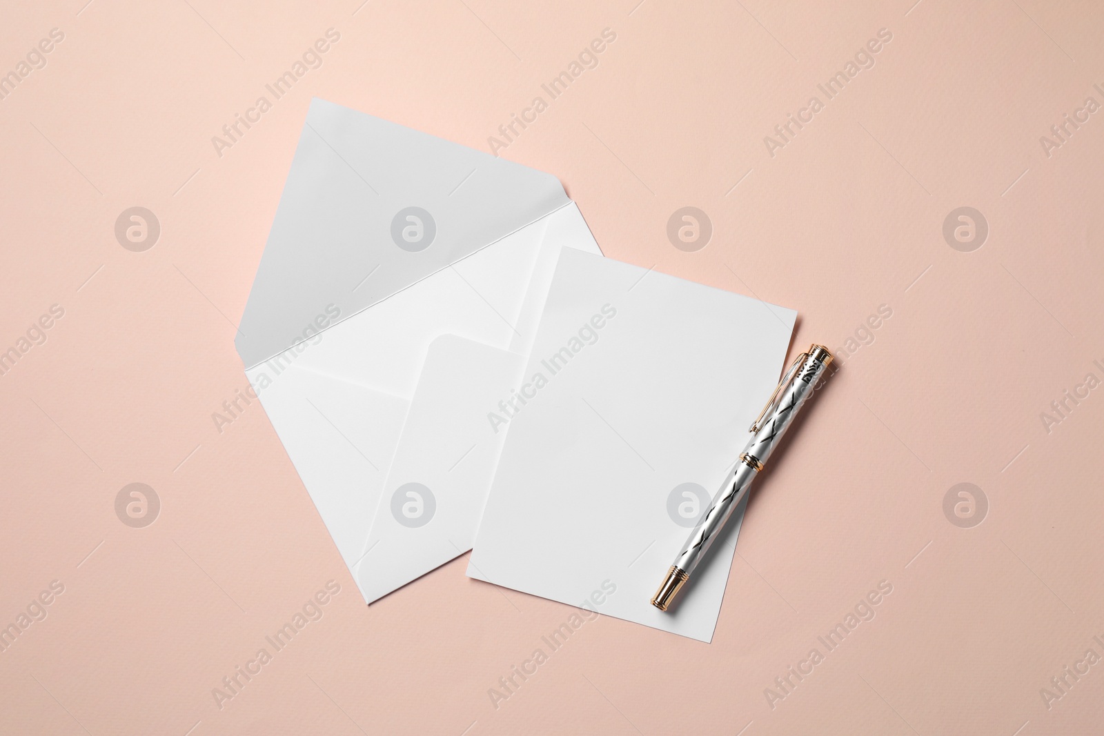 Photo of Blank sheet of paper, letter envelope and pen on beige background, top view. Space for text