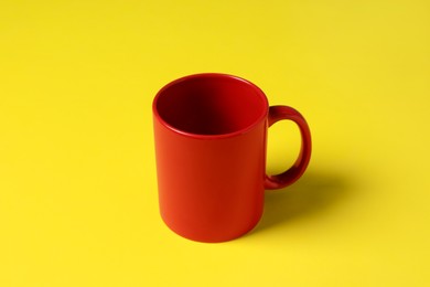 Photo of One red ceramic mug on yellow background
