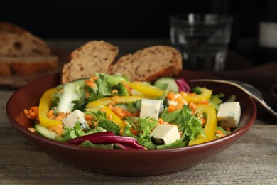 Delicious salad with lentils, vegetables and cheese on wooden table