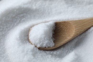 Photo of Wooden spoon on white sea salt, closeup