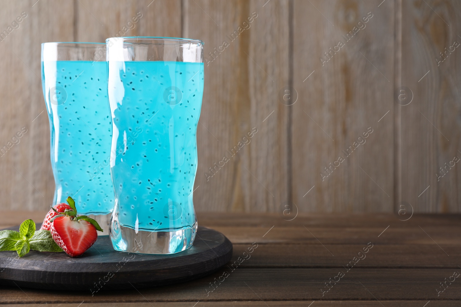 Photo of Delicious cocktail and strawberries on wooden table, space for text