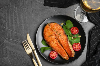 Delicious roasted fish served on grey table, flat lay