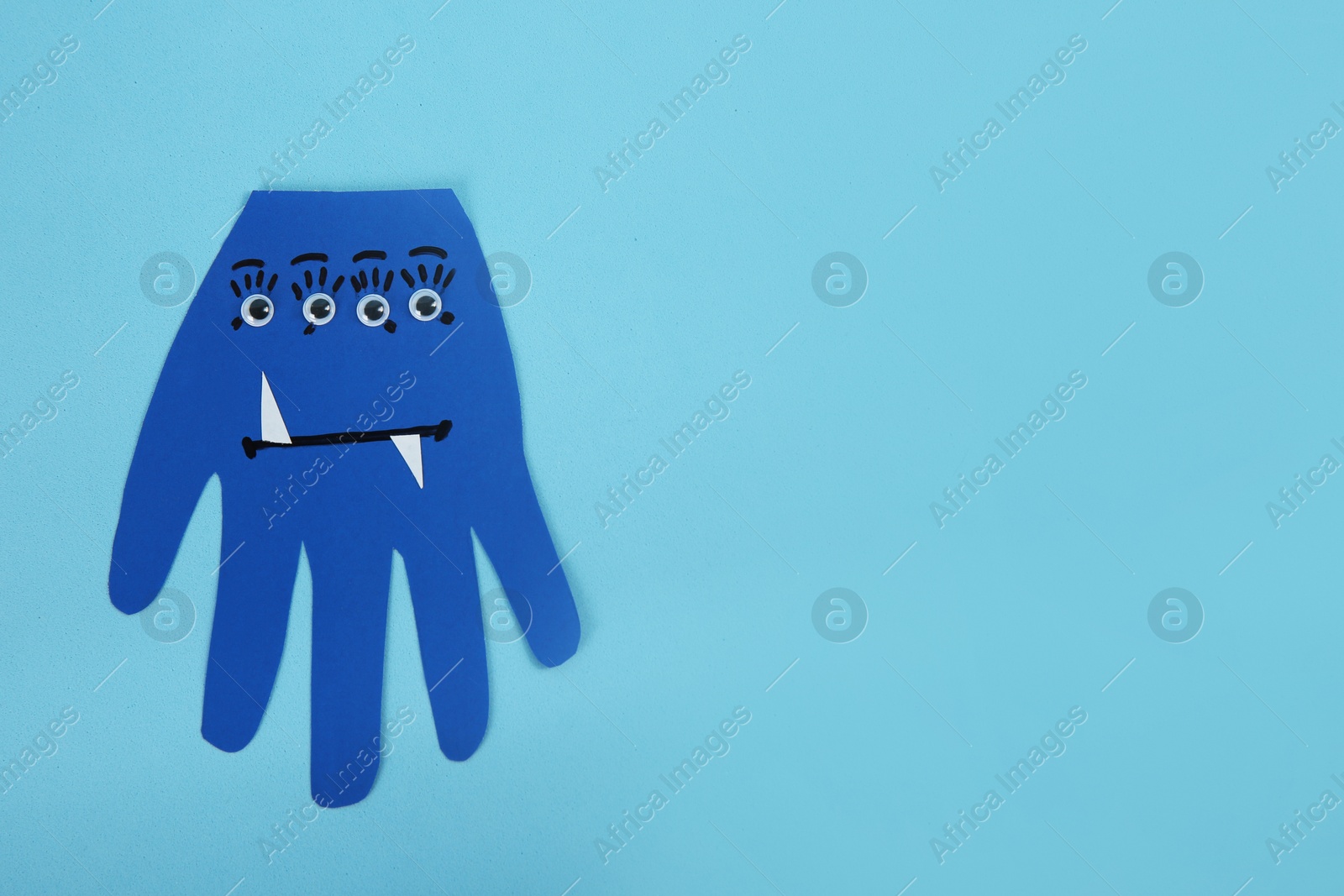 Photo of Funny hand shaped monster on light blue background, top view with space for text. Halloween decoration