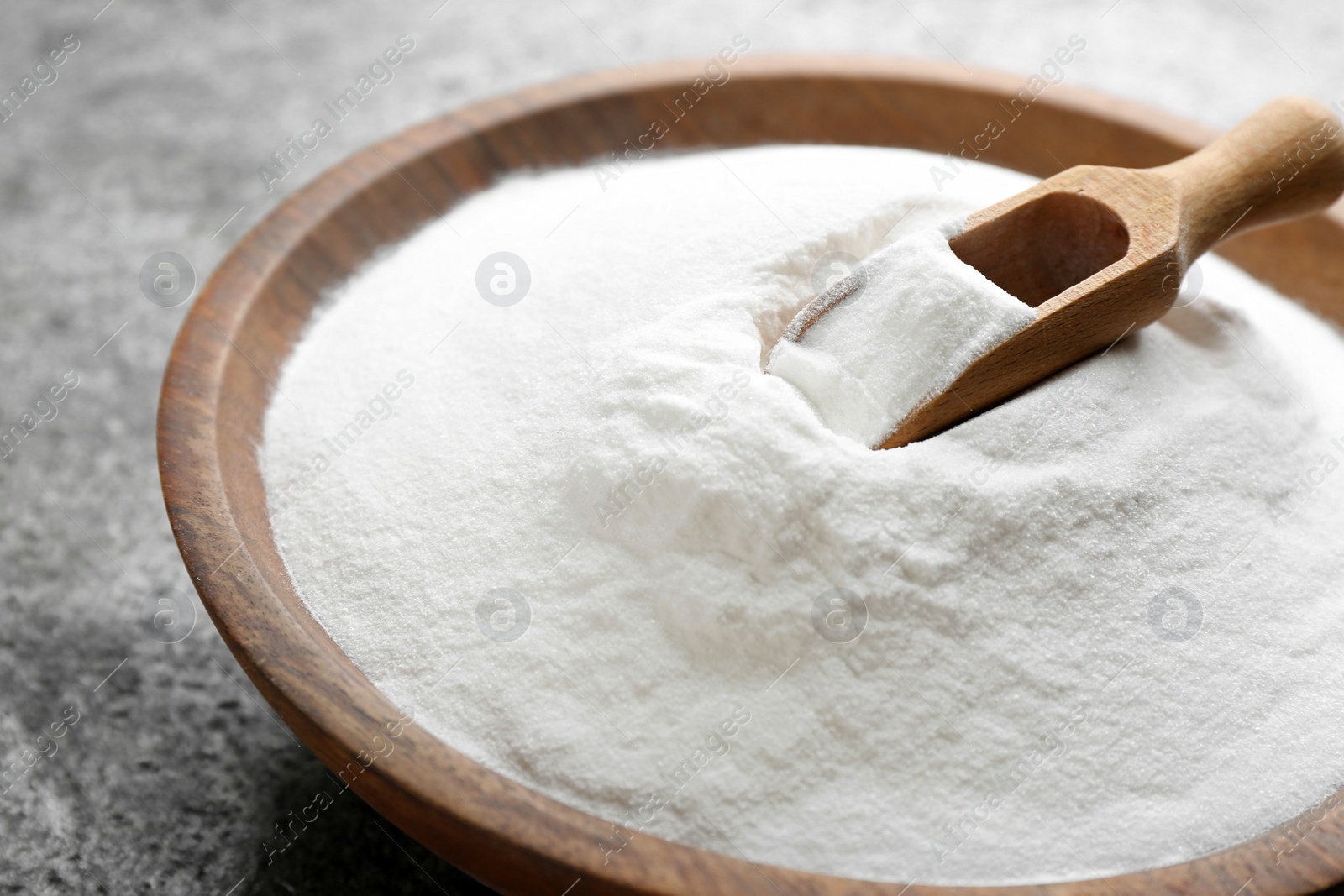 Photo of Baking soda in bowl on grey table, closeup