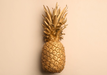 Golden pineapple on beige background, top view. Creative concept