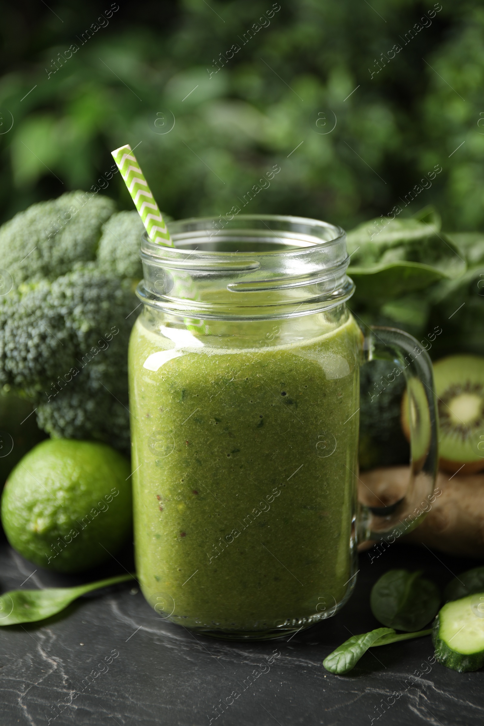 Photo of Delicious green juice and fresh ingredients on black table