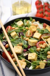 Photo of Bowl of tasty salad with tofu, chickpeas and vegetables on table, closeup