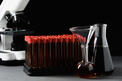 Different laboratory glassware with brown liquids on grey table