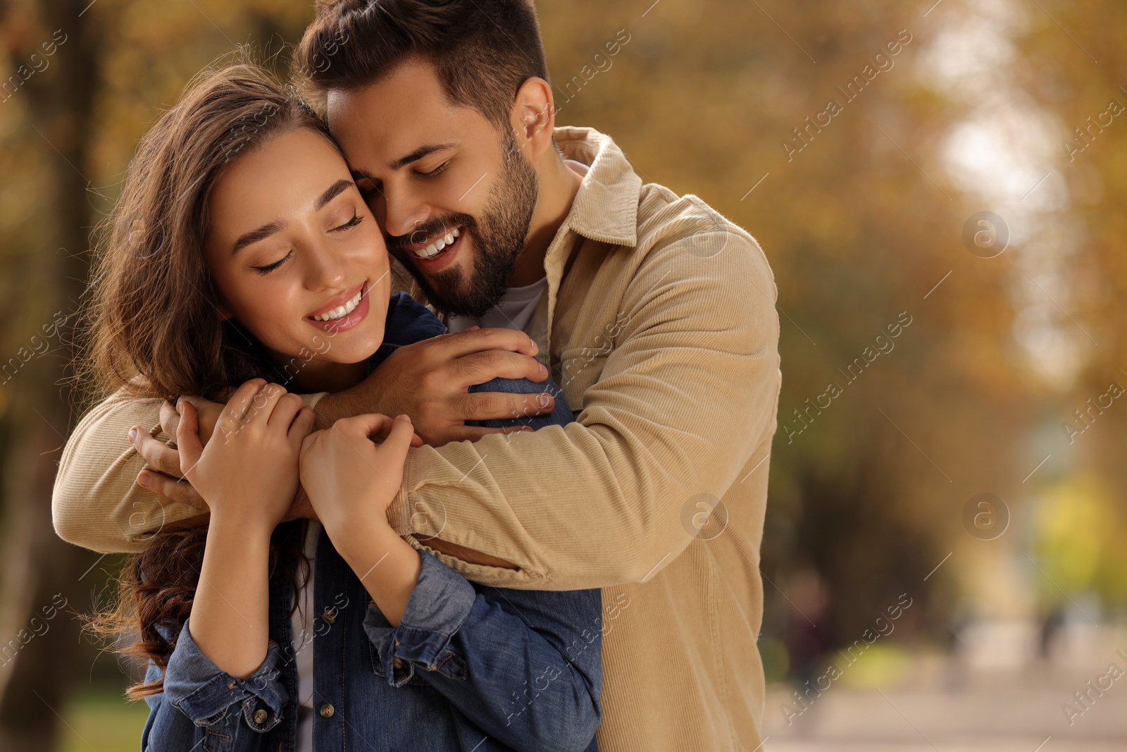 Photo of Beautiful couple hugging in autumn park, space for text