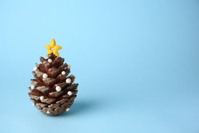 Christmas tree made from pine cone and plasticine on light blue background, space for text. Children's handmade ideas