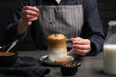 Photo of Woman making dalgona coffee at grey table, closeup