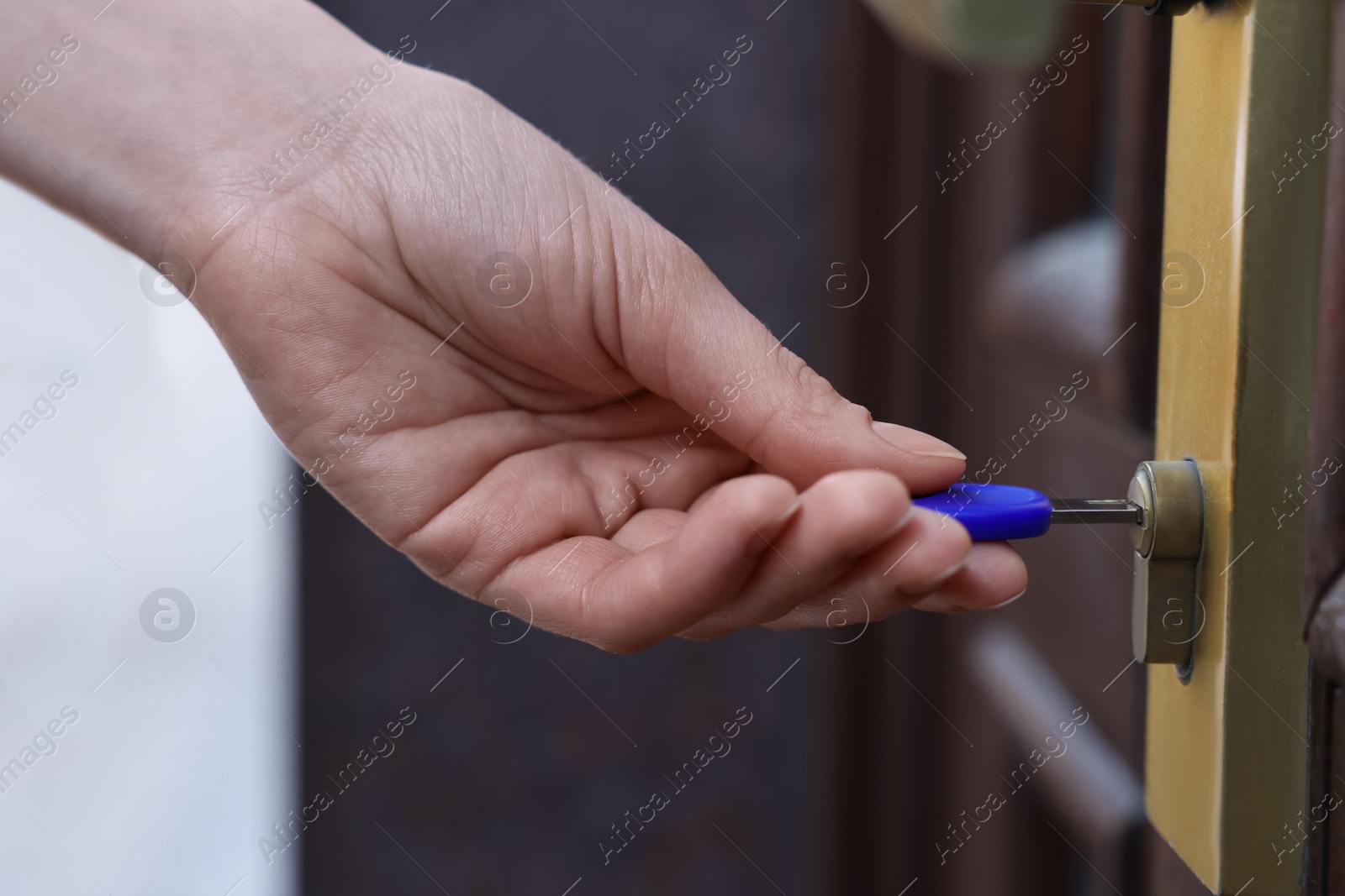 Photo of Woman opening door with key outdoors, closeup