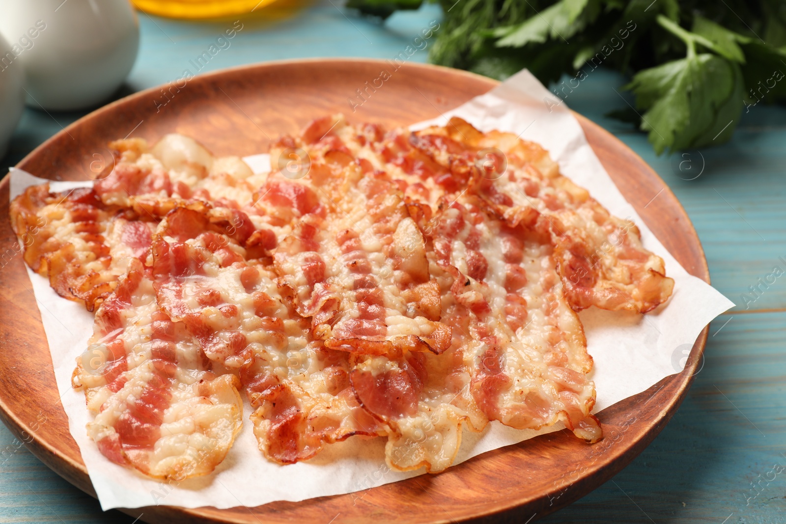 Photo of Delicious fried bacon slices on blue wooden table, closeup