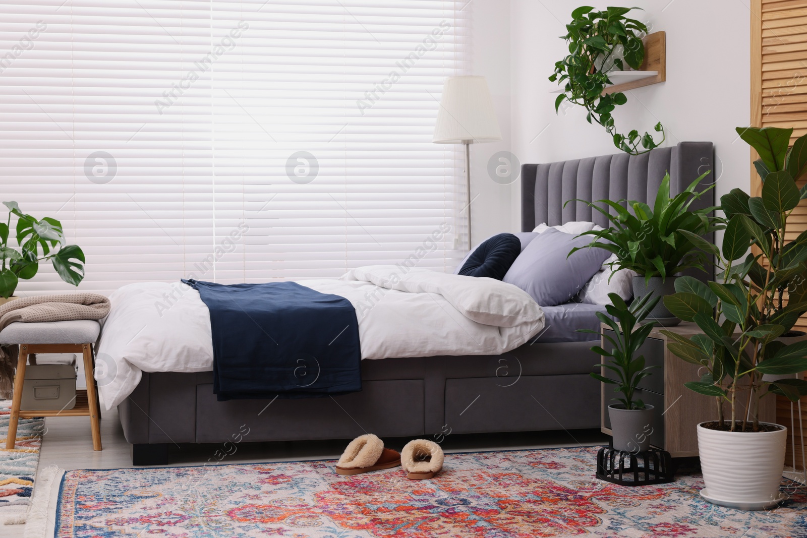 Photo of Stylish bedroom with double bed and beautiful green houseplants. Modern interior