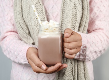 Photo of Woman holding mason jar of delicious cocoa drink with marshmallows, closeup