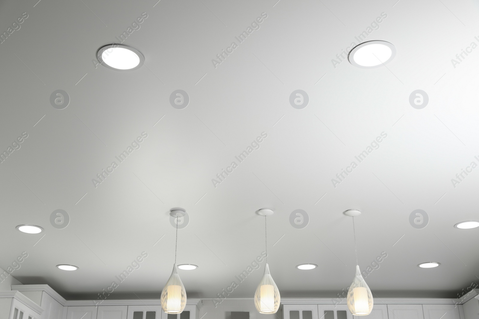 Photo of Modern pendant lamps on white ceiling indoors