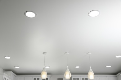 Modern pendant lamps on white ceiling indoors