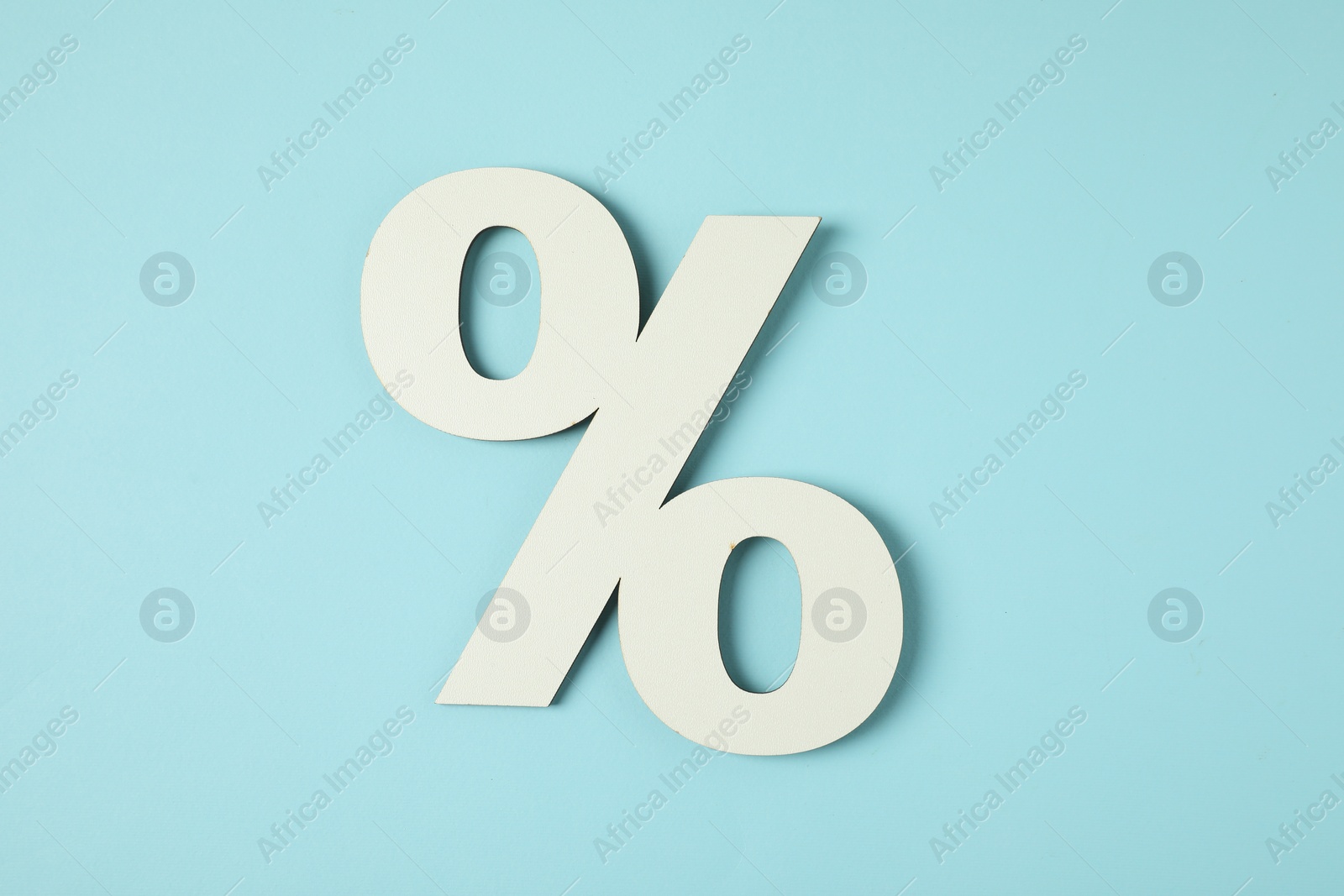 Photo of White percent sign on light blue background, top view