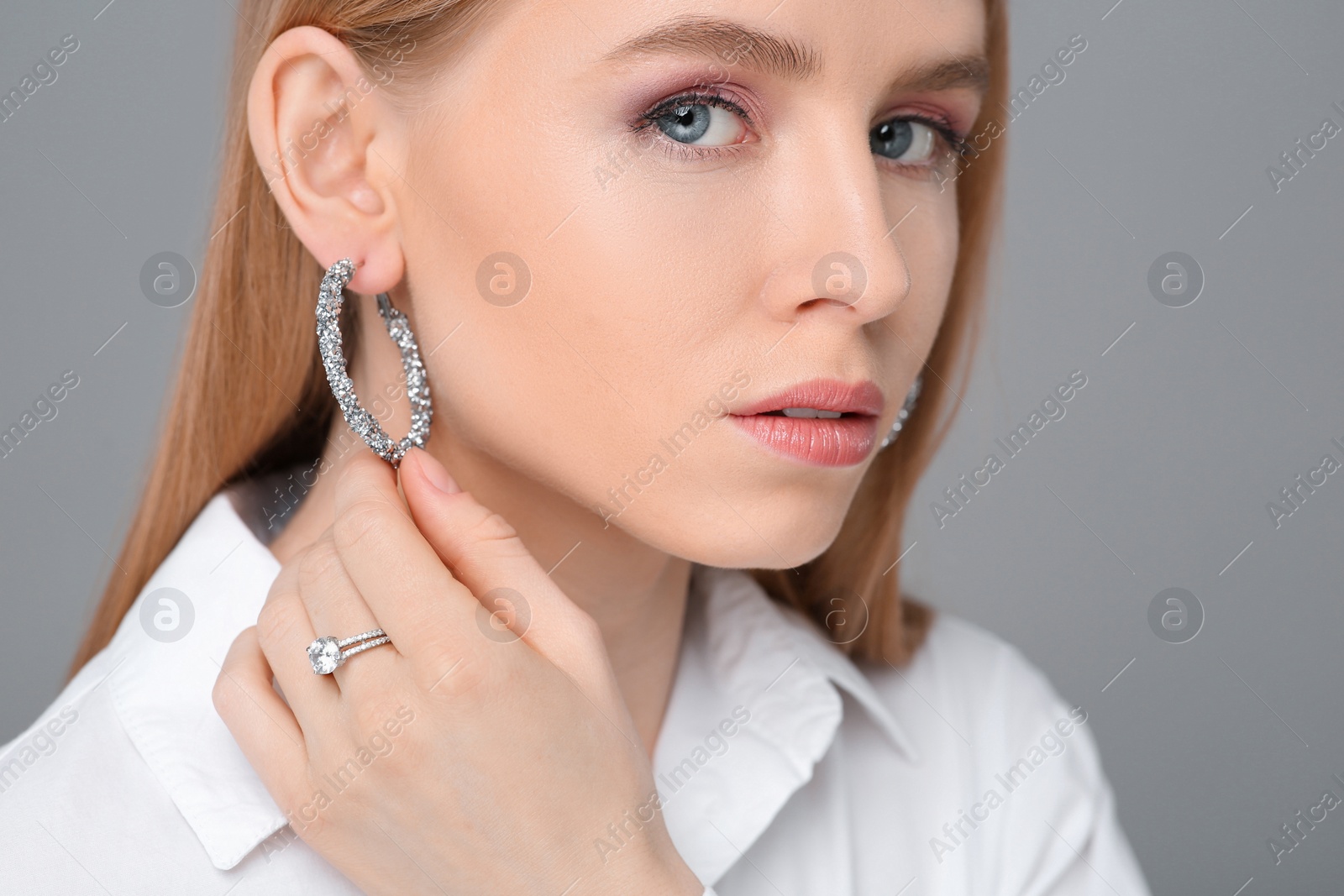 Photo of Beautiful young woman with elegant jewelry on gray background, closeup