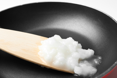 Photo of Frying pan with coconut oil and wooden spatula, closeup. Healthy cooking