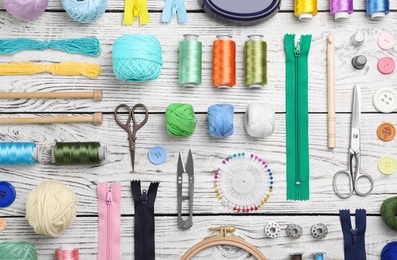 Composition with color threads and sewing accessories on wooden background, top view