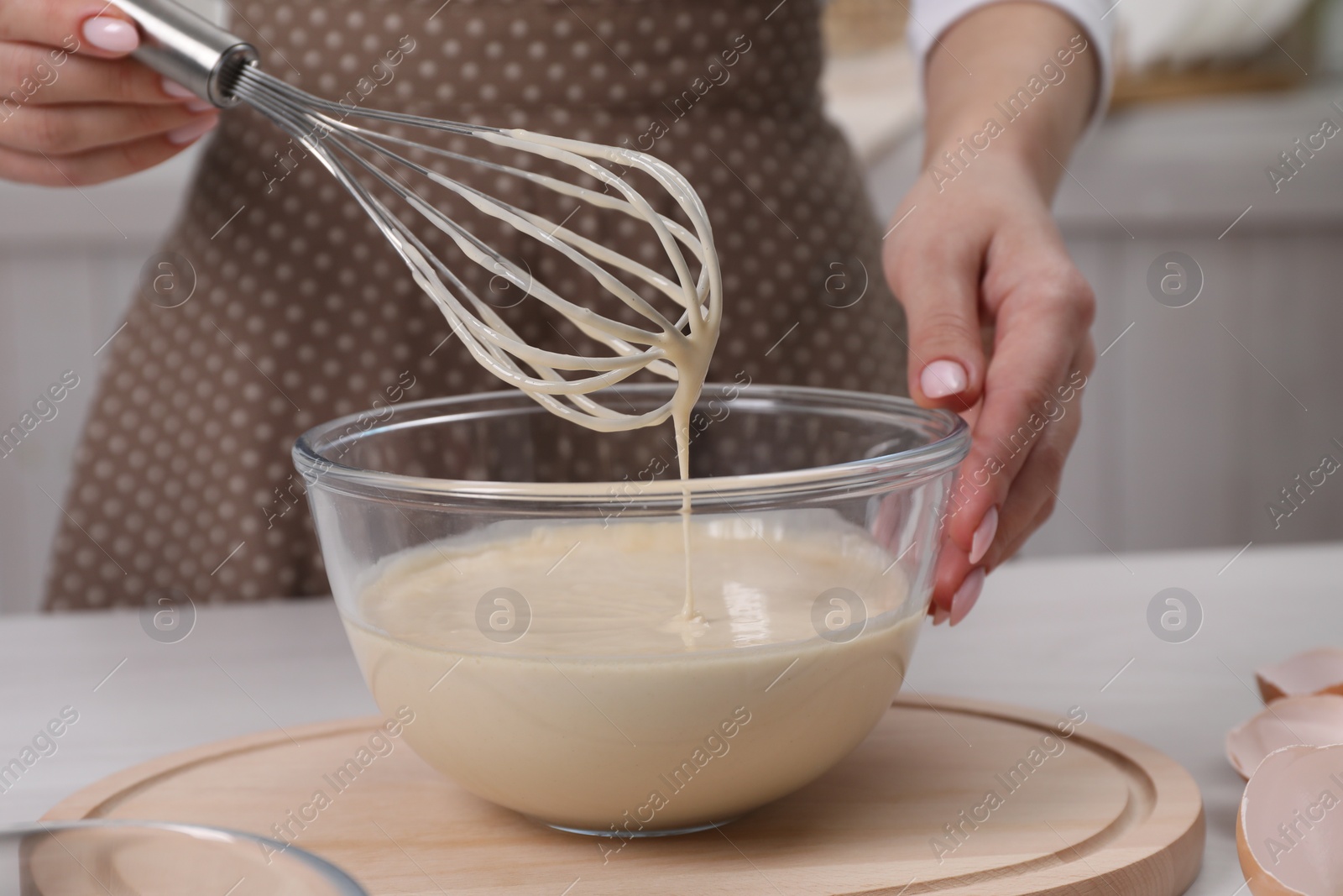 Photo of Woman making dough with whisk in bowl at table, closeup