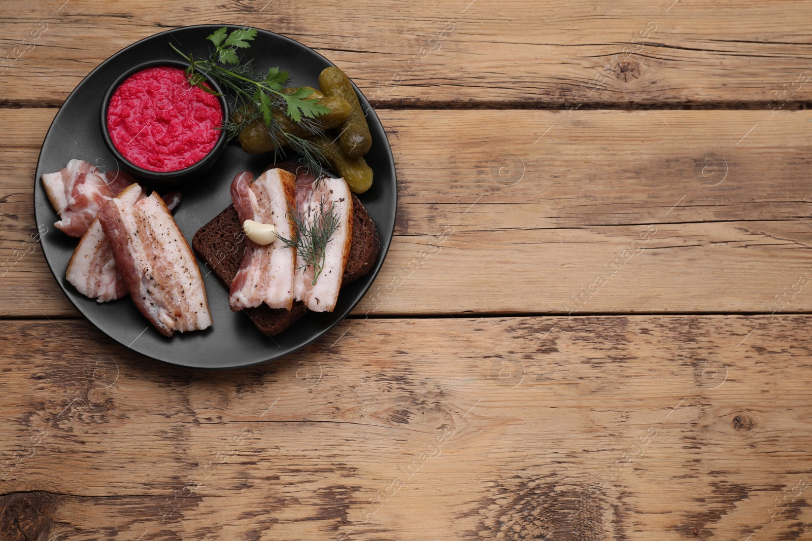 Photo of Tasty pork fatback served on wooden table, top view. Space for text