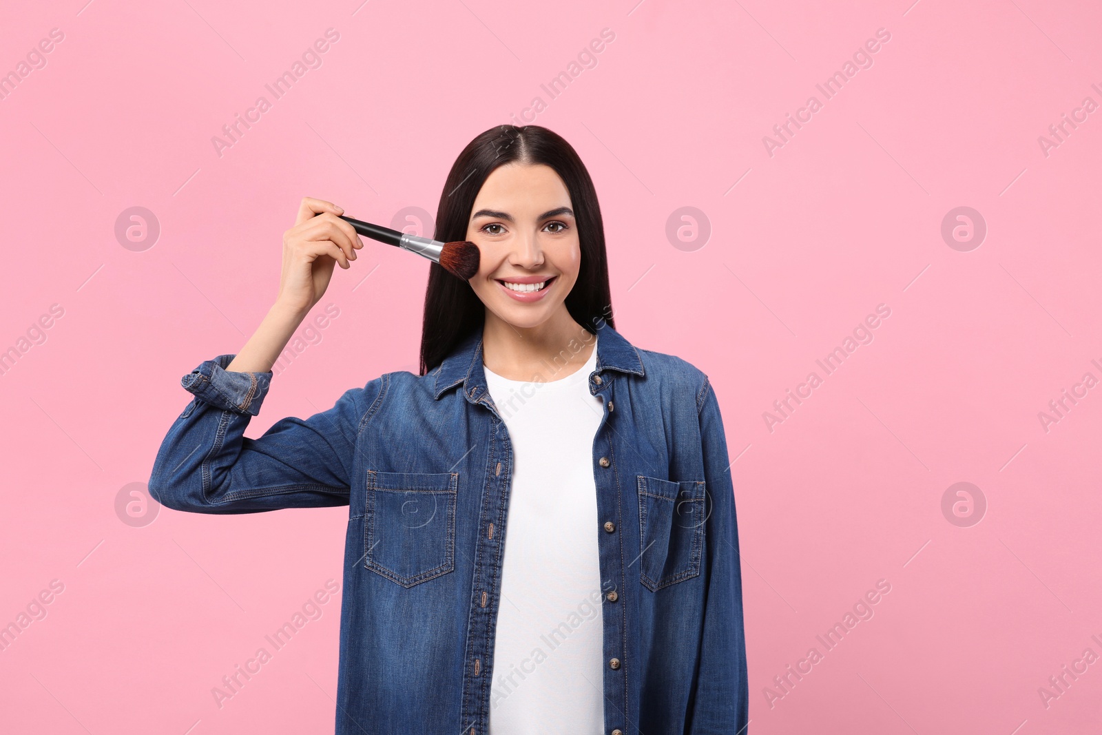 Photo of Portrait of beautiful woman with makeup brush on pink background. Space for text