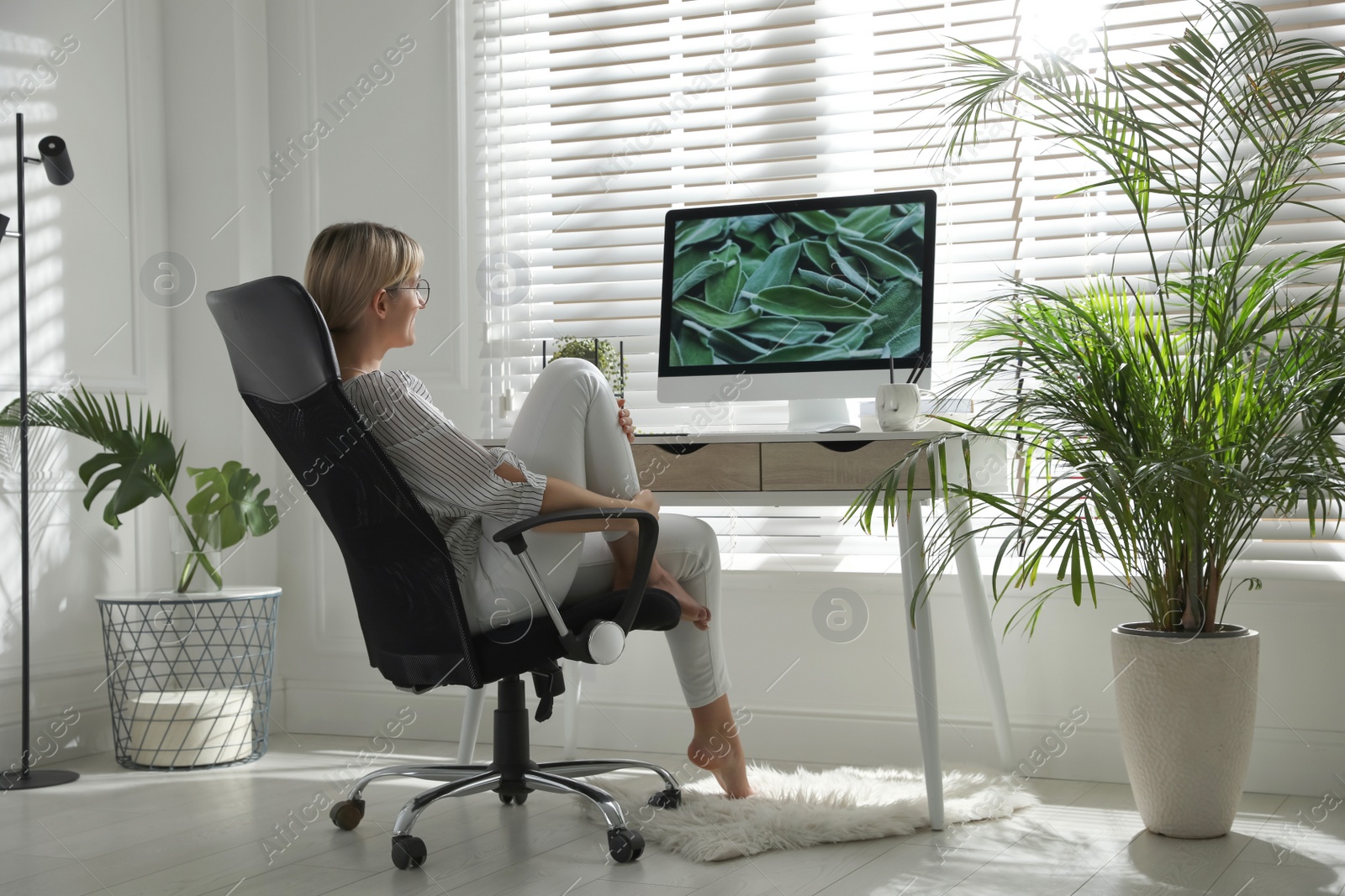 Photo of Woman resting on chair near workplace in room. Interior design