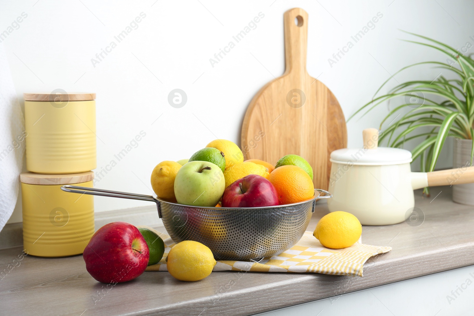 Photo of Metal colander with different fruits on countertop in kitchen