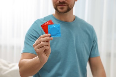 Photo of Closeup of man showing packs with condoms indoors