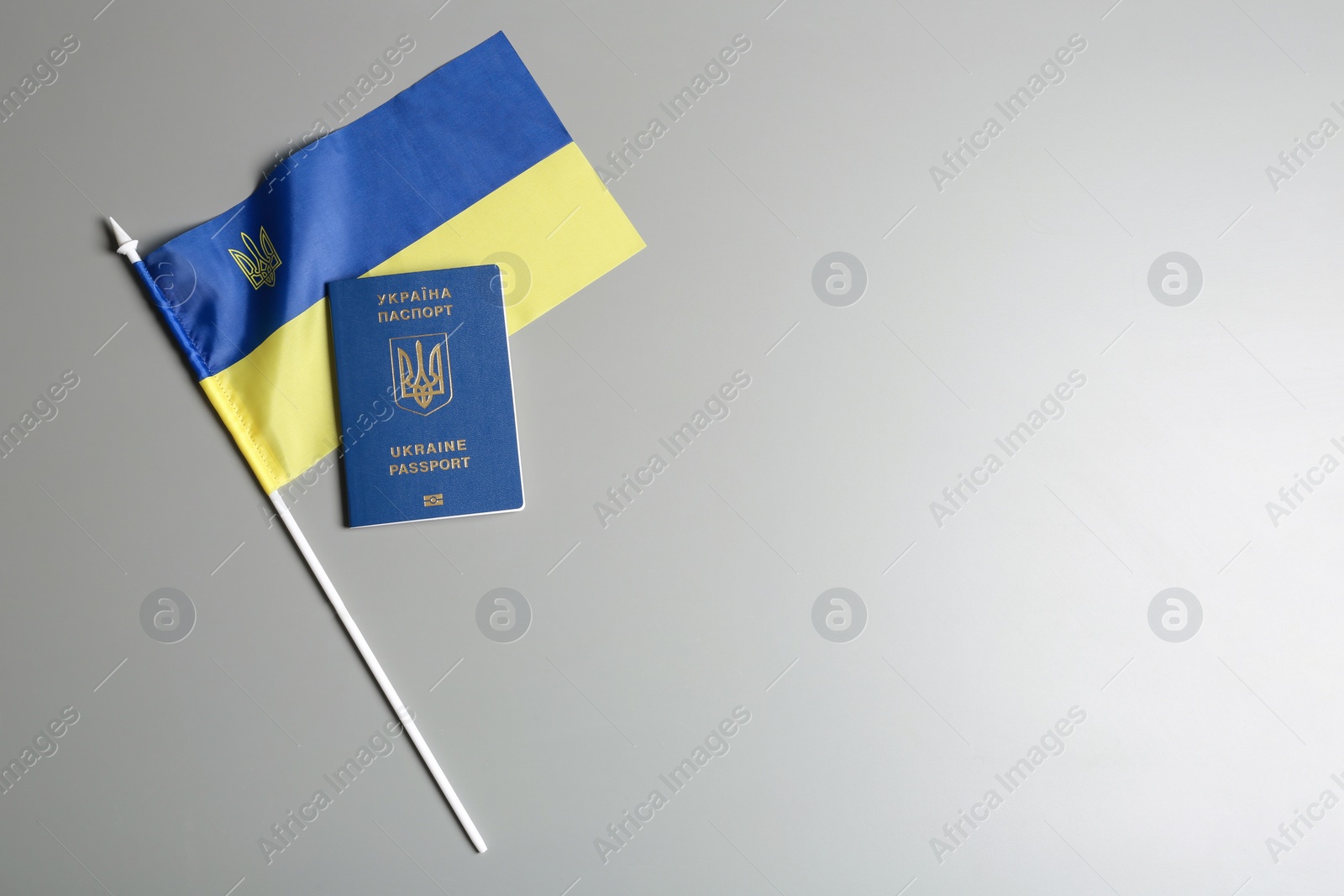 Photo of Ukrainian travel passport and national flag on grey background, top view with space for text. International relationships